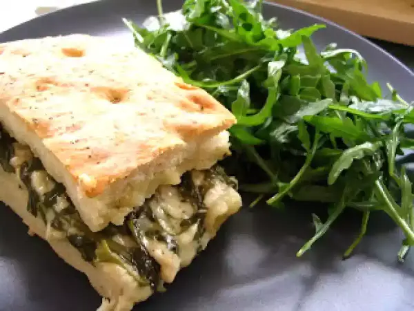 Une focaccia au fromage généreusement garnie d'épinards, servie avec une salade verte fraîche.