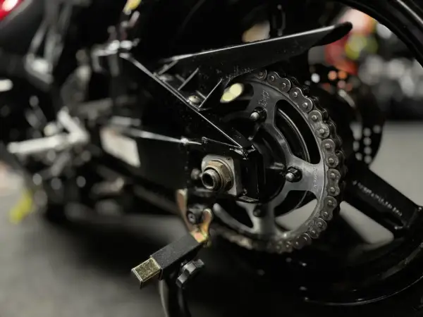 Zbliżenie na tylne koło motocykla z widocznym łańcuchem i zębatką. Pytanie: jaki smar do łańcucha motocyklowego?