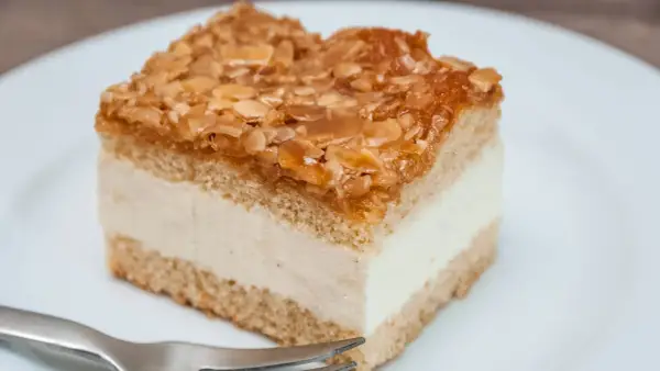 Ein Stück Bienenstich-Kuchen mit cremiger Füllung und karamellisierten Mandeln. Perfekt für das Bienenstich Rezept!