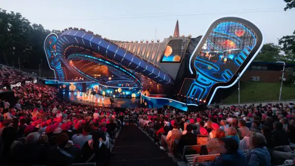 Widownia na festiwalu w Opolu, podziwiająca nowoczesną scenę w kształcie mikrofonu.