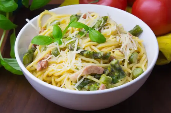 Pyszna carbonara ze szparagami, udekorowana bazylią i parmezanem, czeka na spróbowanie.