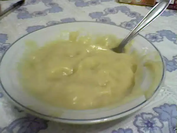 Un tazón blanco con un suave y cremoso puré de pescado, listo para ser disfrutado. Una cuchara plateada descansa en el tazón.