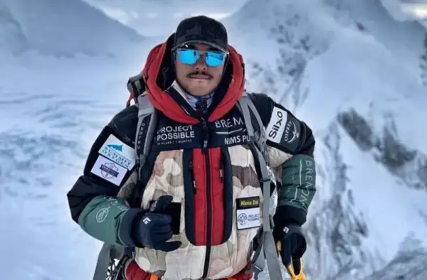 Nims Dai, alpiniste audacieux, porte sa veste "Project Possible" sur les sommets enneigés.