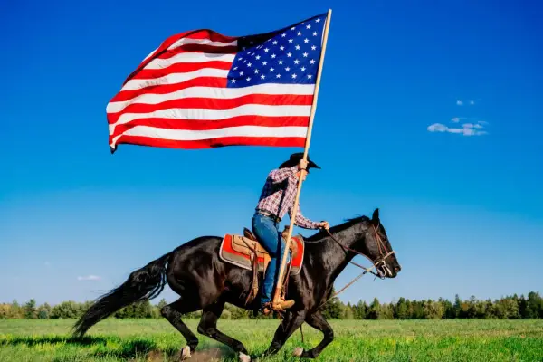 Kowbojka na czarnym koniu niesie flagę USA. To obraz wolności i dzikiego zachodu, pełen ciekawostek o Ameryce.