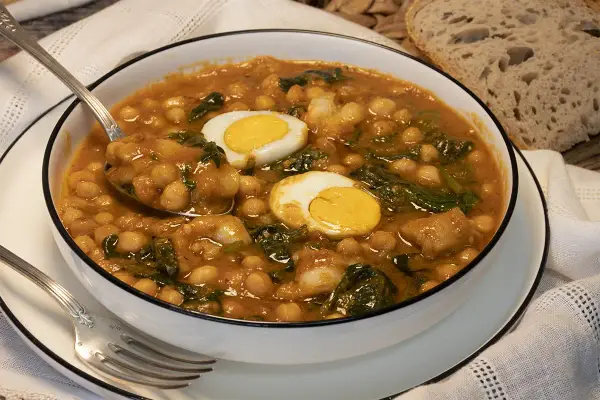 Potaje de garbanzos con bacalao y huevo duro en un cuenco blanco.