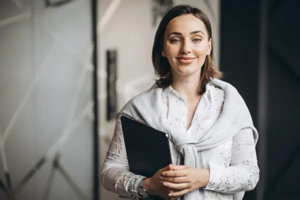 Uśmiechnięta nauczycielka z teczką, przygotowująca się do spełnienia wymagań na nauczyciela mianowanego po staremu.