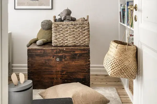 Cesti di vimini per idee arredare con stile: un cesto intrecciato sopra un baule antico, un altro appeso alla porta.