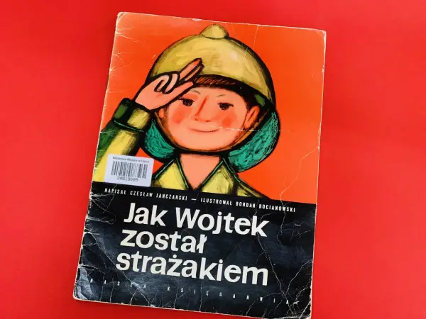 Okładka książki "Jak Wojtek został strażakiem" z ilustracją chłopca w hełmie.
