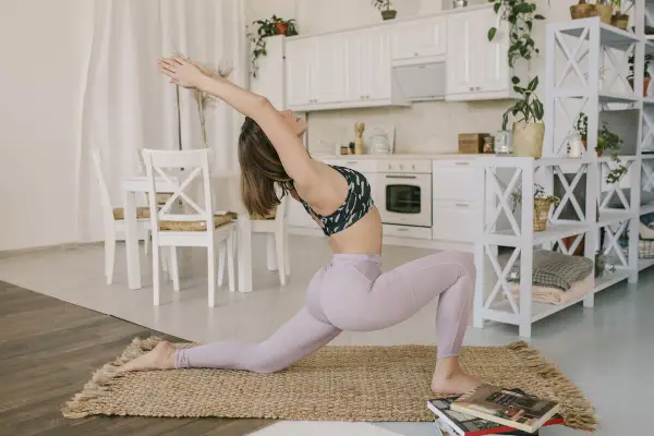 Kobieta w pozycji anjaneyasana rozciąga się w kuchni.