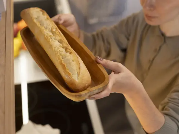 Frau hält Holzschale mit Baguette zum Auftauen.