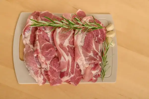 Surowe kawałki wieprzowiny z rozmarynem i czosnkiem, idealne jako jakie mięso do bigosu.