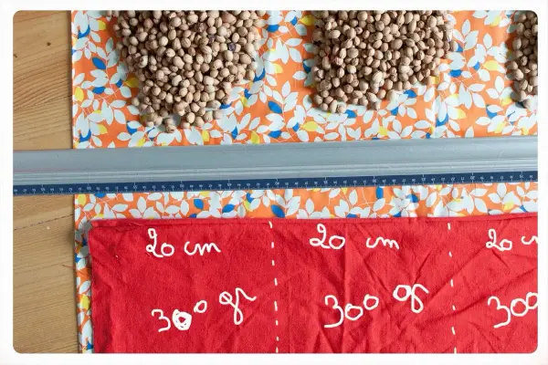 Préparation d'une bouillotte aux noyaux de cerise. Quel tissu choisir ? Ici, un coton imprimé et un tissu rouge marqué pour la découpe.