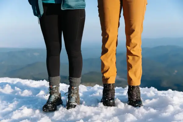 Dwie pary solidnych butów trekkingowych, niczym nowoczesne walonki, stoją na śniegu.