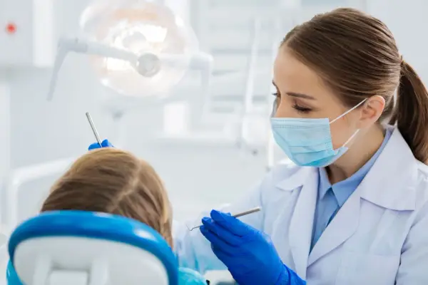 Dentystka bada uśmiech dziecka, by wykluczyć zapalenie dziąseł.