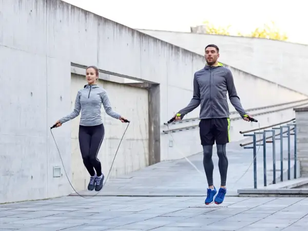 Ein Paar macht ein intensives **Springseil Workout** im Freien vor einer Betonwand.
