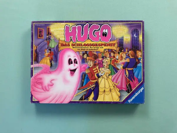 Das Cover des Hugo Spiels zeigt ein rosa Gespenst, das eine Ballgesellschaft erschreckt. Wer ist mutig genug, sich vor Hugo in Sicherheit zu bringen?