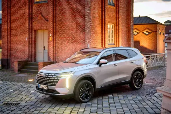 Srebrny Haval SUV zaparkowany na brukowanym dziedzińcu przed ceglanym budynkiem.