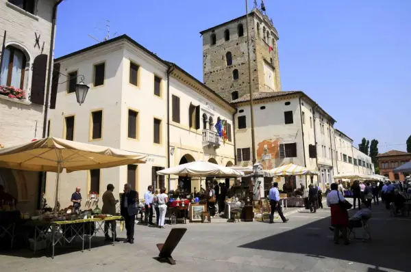 Mercato in piazza a Portobuffolè cosa vedere: bancarelle di antiquariato e la torre civica sullo sfondo.