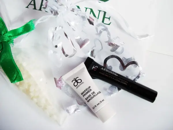Arbonne opinie: zestaw kosmetyków z primerem i tuszem, w ozdobnym woreczku.
