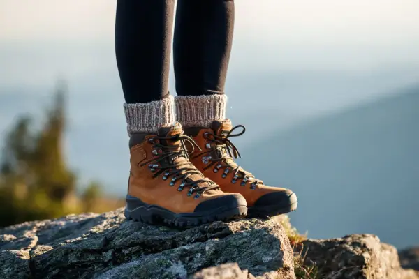 Braune Wanderschuhe mit dicken Schnürsenkeln und Strickstulpen. Die richtige Wahl, welche Socken zum Wandern, ist entscheidend für Komfort.