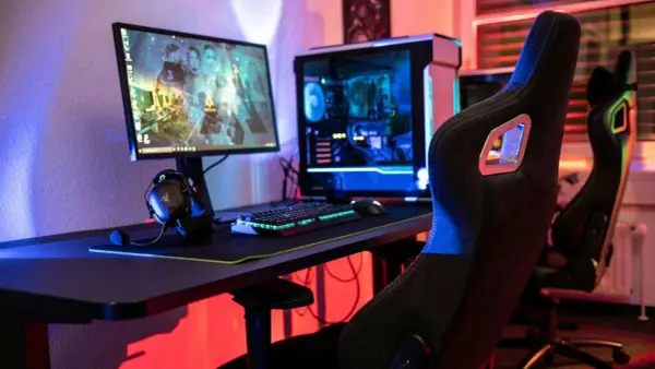 Gaming-Setup mit beleuchtetem PC, Tastatur und Kopfhörern. Der **Atlas OS**-Desktop zeigt ein Spiel.