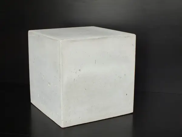 Ein Würfel aus hellem Beton C30/37 steht auf schwarzem Untergrund.