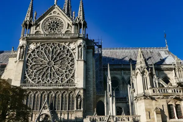 Katedra Notre-Dame z rozetą i wieżyczkami na tle błękitnego nieba.