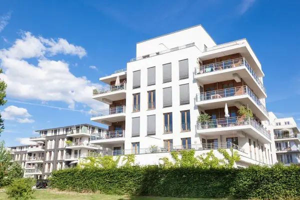Immeubles modernes avec balcons fleuris, sous un ciel bleu. Un projet immobilier qui pourrait bénéficier de la loi Borloo pour son accessibilité.