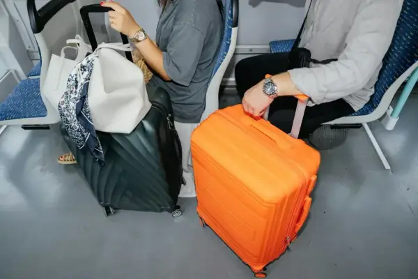 Podróżni z bagażami, w tym pomarańczową walizką, przygotowują się do lotu. Nadbagaż lot.