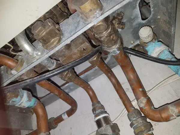 Instalacja pieca gazowego Vaillant z miedzianymi rurami. Widoczne przyłącza i zawory, być może problem ze słabym ciśnieniem ciepłej wody.
