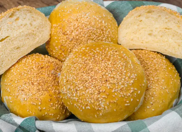 Koszyk pełen pysznych, złotych bułek bez drożdży, posypanych sezamem. Idealne na burgery lub jako dodatek do posiłku.