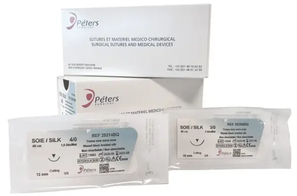 Opakowania z szwami chirurgicznymi Peters Surgical. Widać dwa pakiety z szwami jedwabnymi, w tym jeden z igłą tnącą.