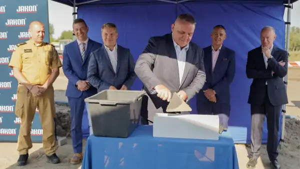Uroczyste wmurowanie kamienia węgielnego. Mężczyzna w garniturze z kielnią w dłoni symbolicznie rozpoczyna budowę.