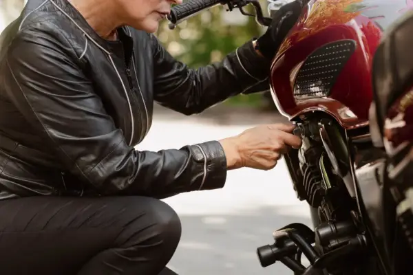 Kobieta w skórzanej kurtce sprawdza regulator napięcia alternatora w motocyklu.