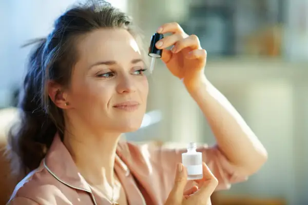 Kobieta aplikuje serum z **retinalem** na skórę pod okiem, dbając o młody wygląd.