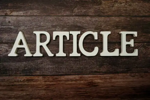 Białe litery układają się w słowo "ARTICLE" na drewnianym tle. To zapowiedź rozszerzonego artykułu po angielsku.