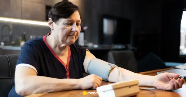 Kobieta mierzy ciśnienie skurczowe w domu. Na ramieniu ma mankiet ciśnieniomierza.
