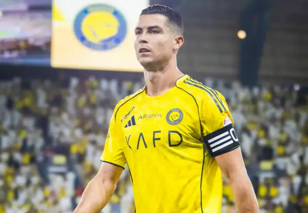 Cristiano Ronaldo w żółtej koszulce Al Nassr, z opaską kapitana na ramieniu, na tle trybun pełnych kibiców.
