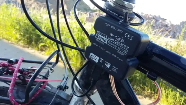 Ładowarka rowerowa Kemo zasilana przez **dynamo**, podłączona do kierownicy, z kablem USB.