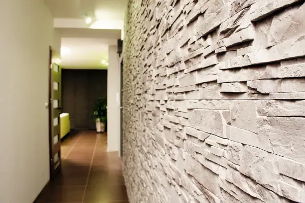 Kamienna ściana w wąskim przedpokoju dodaje charakteru. Idealna tapeta, która optycznie poszerzy przestrzeń.