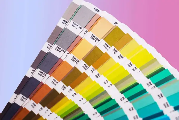 Próbnik kolorów Pantone prezentuje bogactwo barw, od stonowanych szarości po jaskrawe zielenie i żółcie. To narzędzie niezbędne w praktycznym zastosowaniu teorii koloru.