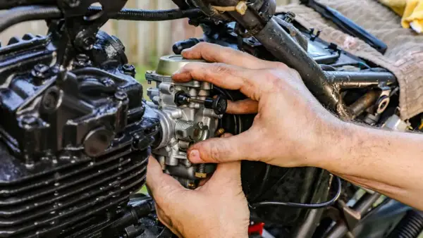 Manos ajustando el ahogador de moto, pieza clave para el arranque en frío.