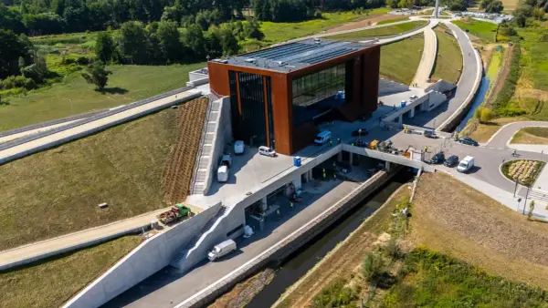 Nowoczesny budynek muzeum bitwy warszawskiej z cortenowską fasadą, otoczony zielenią i betonowymi konstrukcjami.