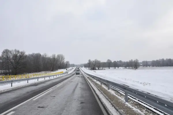 Zimowa trasa, śnieg przy drodze, drzewa bez liści. Nowy tomyśl trasa wita podróżnych.