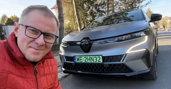 Mężczyzna w czerwonej kurtce robi selfie z nowym Renault Megane E-Tech.