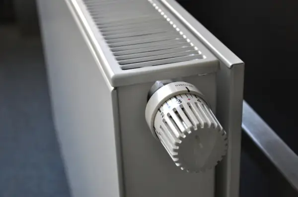Biały grzejnik z termostatem ustawionym na 3. To element ogrzewania elektrycznego mieszkania, zapewniający komfort cieplny.