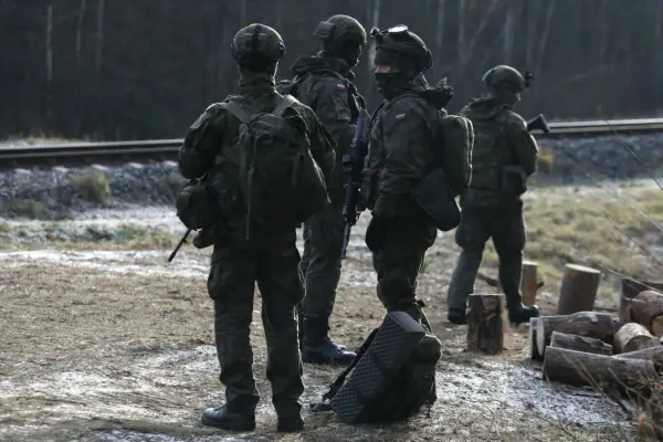 Szeregowi w wojsku patrolują teren przy torach kolejowych, gotowi do akcji.