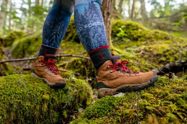 Hiking boots on mossy ground. Learn how to know if boots are too big by checking for heel slip and toe room.