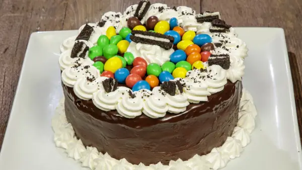 Torta al cioccolato con panna, caramelle colorate e biscotti Oreo, un'esplosione di gusto per torte di compleanno particolari.