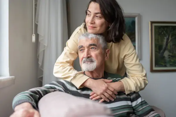 Un uomo anziano con Alzheimer, abbracciato da una donna, sembra cogliere un momento di lucidità, un ricordo che riaffiora.